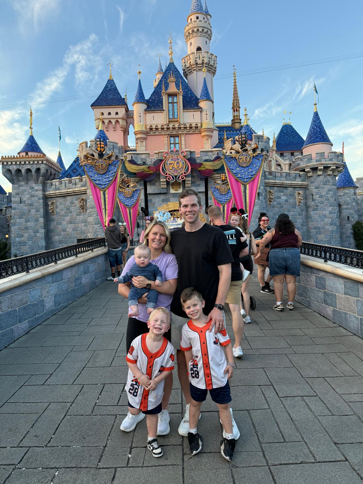 Family of five posing in front of Sleeping Beauty Castle at Disneyland