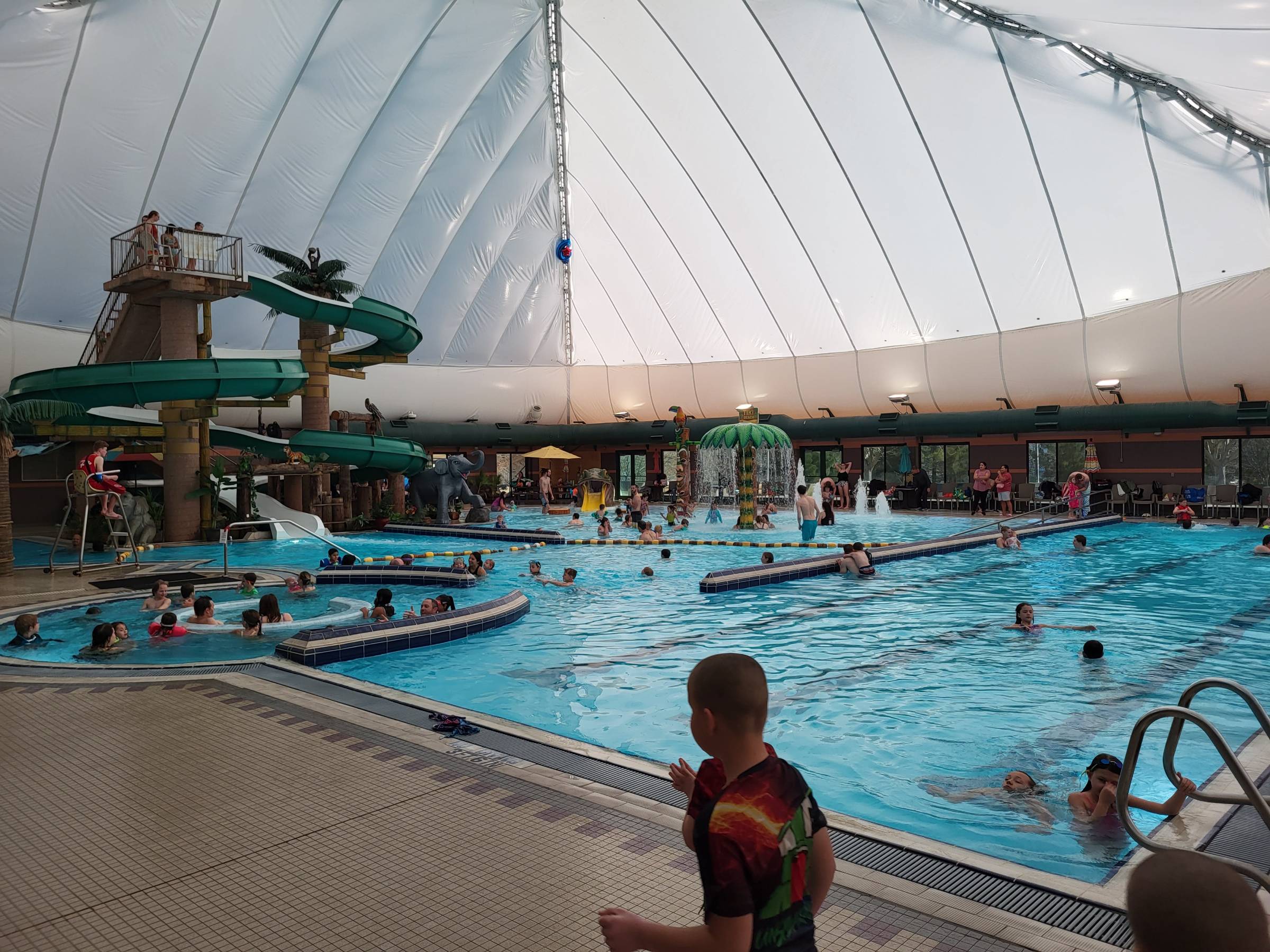 Families swimming in the indoor Sand Hollow Aquatic Center pools, with water slides and a domed roof overhead
